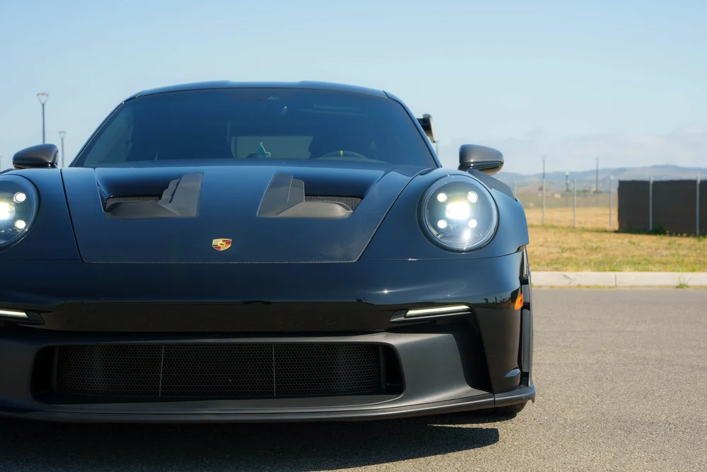 Black Porsche 992.1 GT3 RS, front detail with round headlights, hood openings and front intake