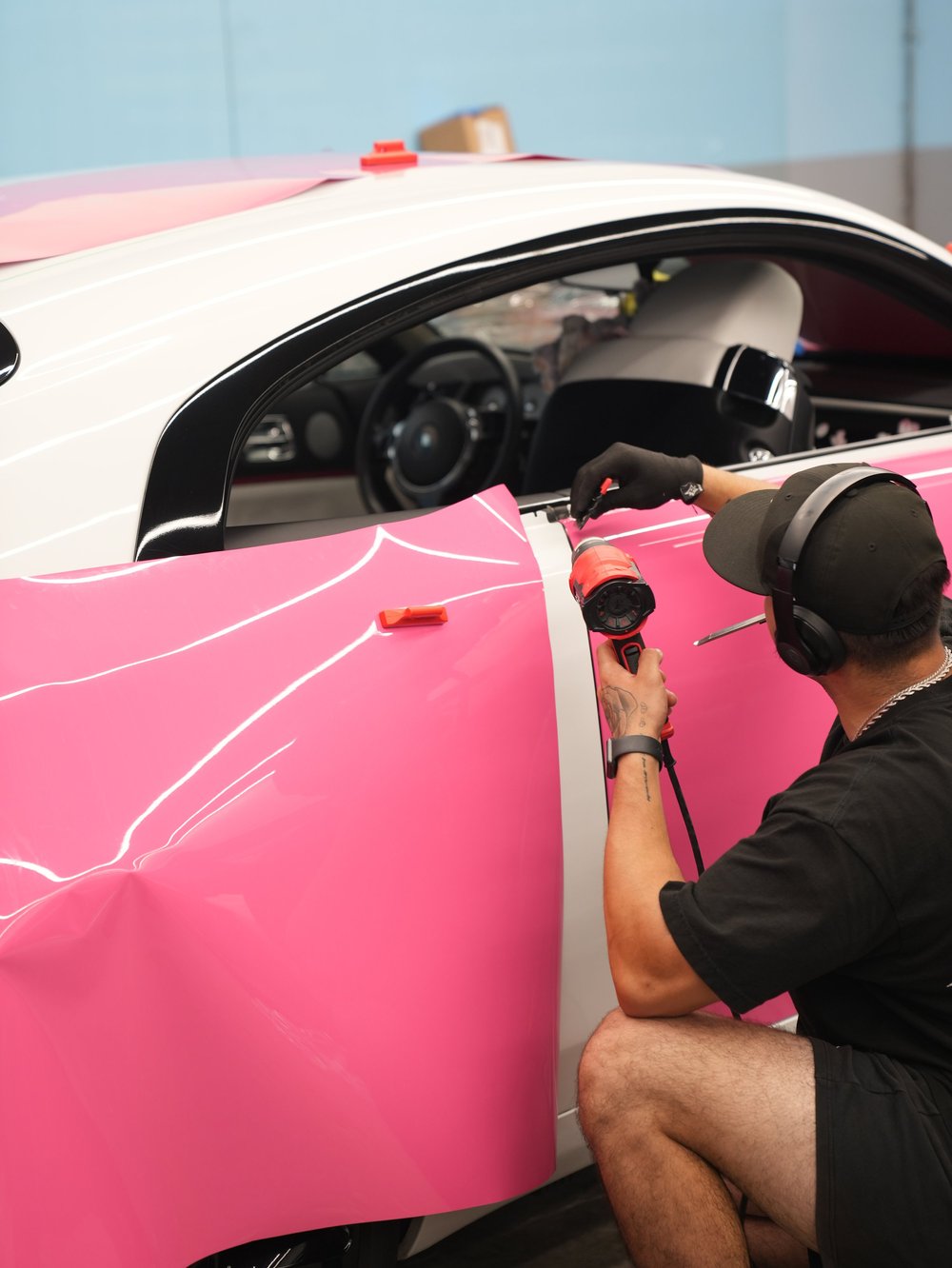 Technician applying Rose Pink vinyl along the Wraith door with a heat gun