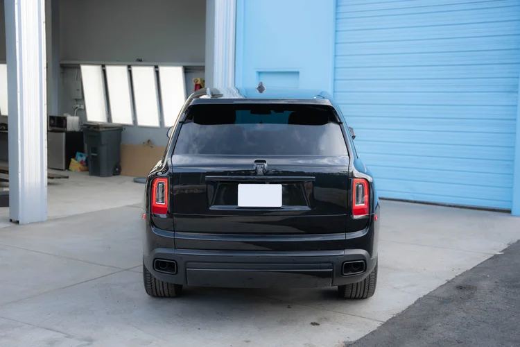 Black SUV facing away from the camera with both rear wheels and lamps visible.