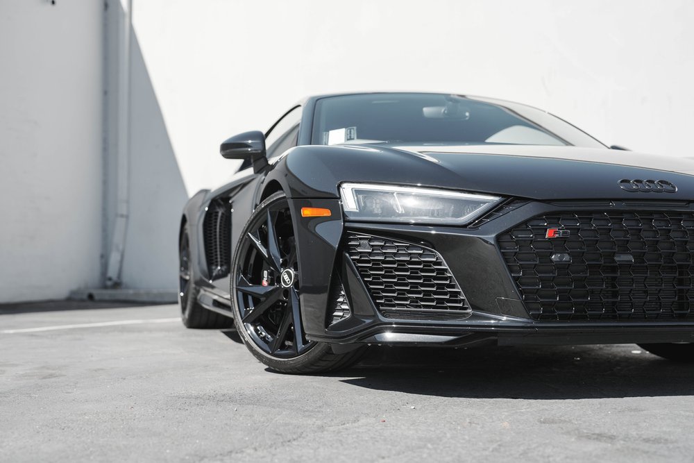 Low close front-quarter view of the Audi R8 with angular headlight, dark grille and black front wheel