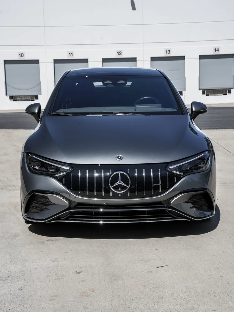 Centered front view of the gray Mercedes-AMG EQE 53 with dark windshield, star grille and lower bumper.