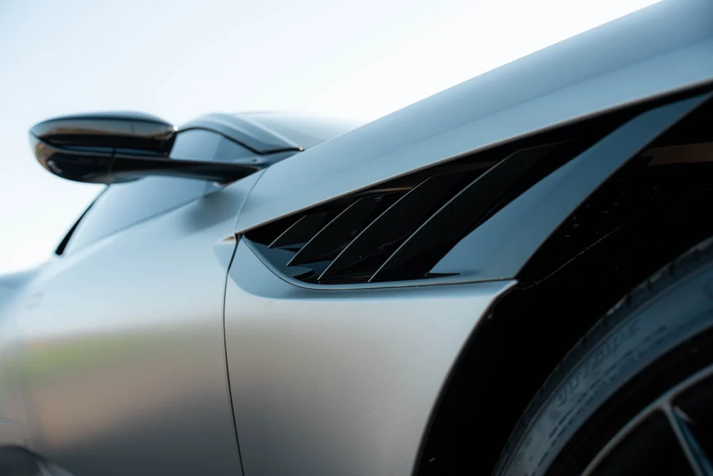 Close view of the DBS dark side vent and mirror against matte bodywork beside the front wheel arch