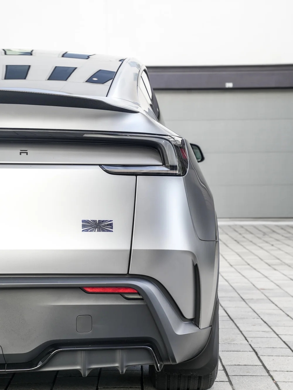 Rear detail of the Model Y Performance showing the carbon-fiber spoiler edge above the rear light bar and satin tailgate.