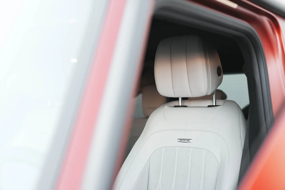 Light-colored G63 front seat and headrest viewed through the open red door frame