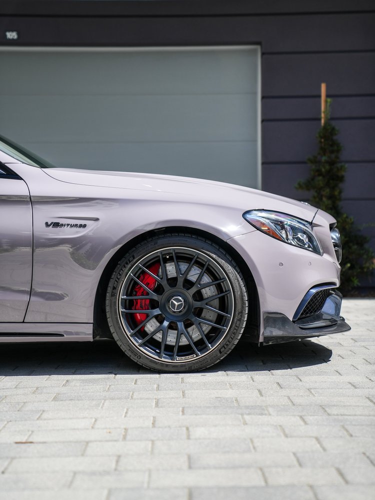 Front wheel, red brake caliper, light-grey fender and bumper corner in a closer side view of the C 63 S
