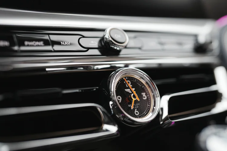 Round dashboard clock with orange hands beneath the center controls.