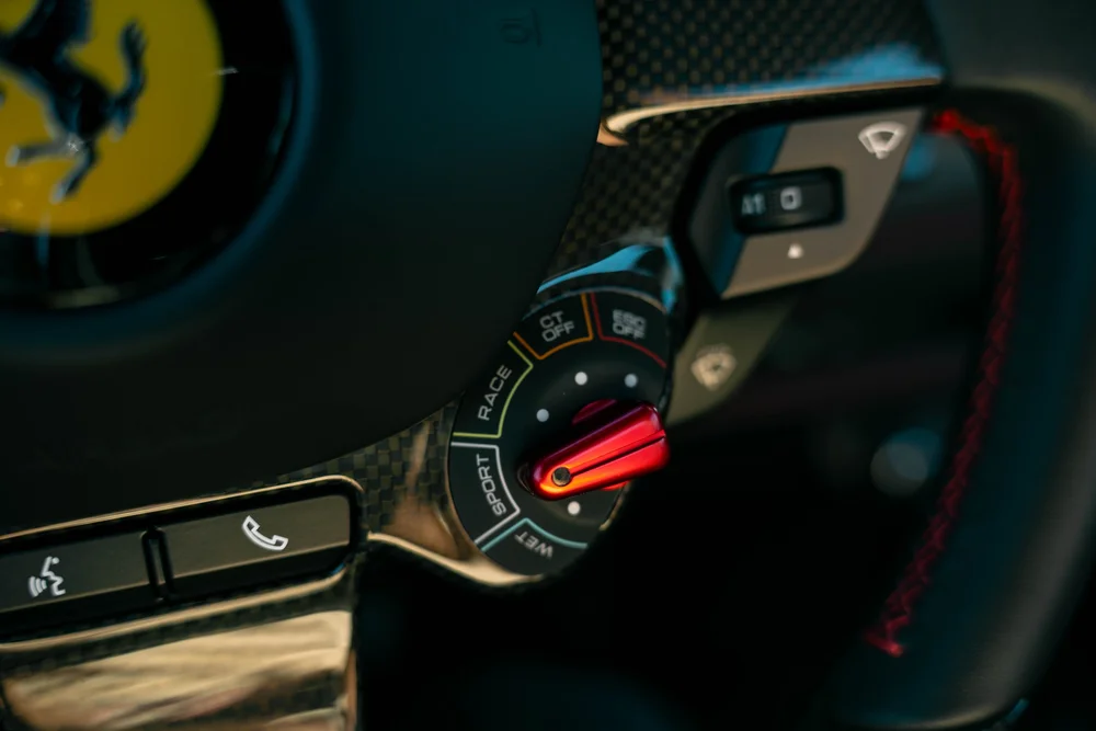 Ferrari F8 steering-wheel drive-mode switch beside red stitching
