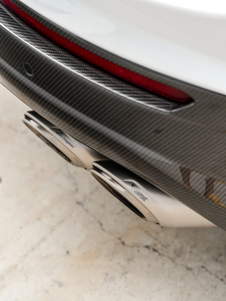 Red lower rear reflector above woven-pattern bumper trim and two metal exhaust outlets with visible lettering.