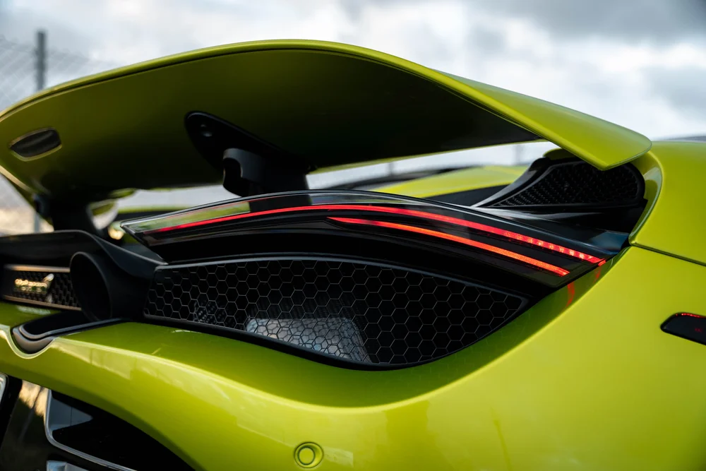 Green McLaren 720S raised rear wing above an illuminated taillight and honeycomb grille