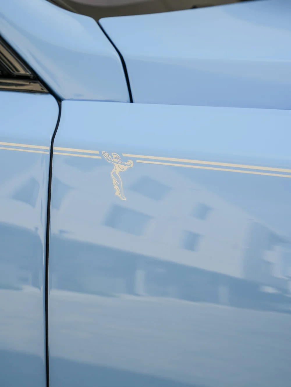 Factory gold coachline and Spirit of Ecstasy motif on the Powder Blue Cullinan exterior beside a panel seam