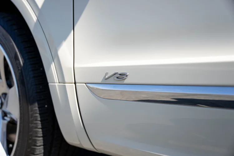 V8 badge and silver lower-door trim beside the front wheel.