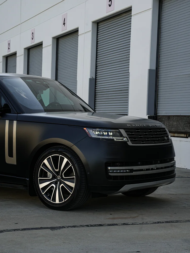 Front-quarter detail of the black Range Rover, showing its wheel, headlamp, grille and bonnet.