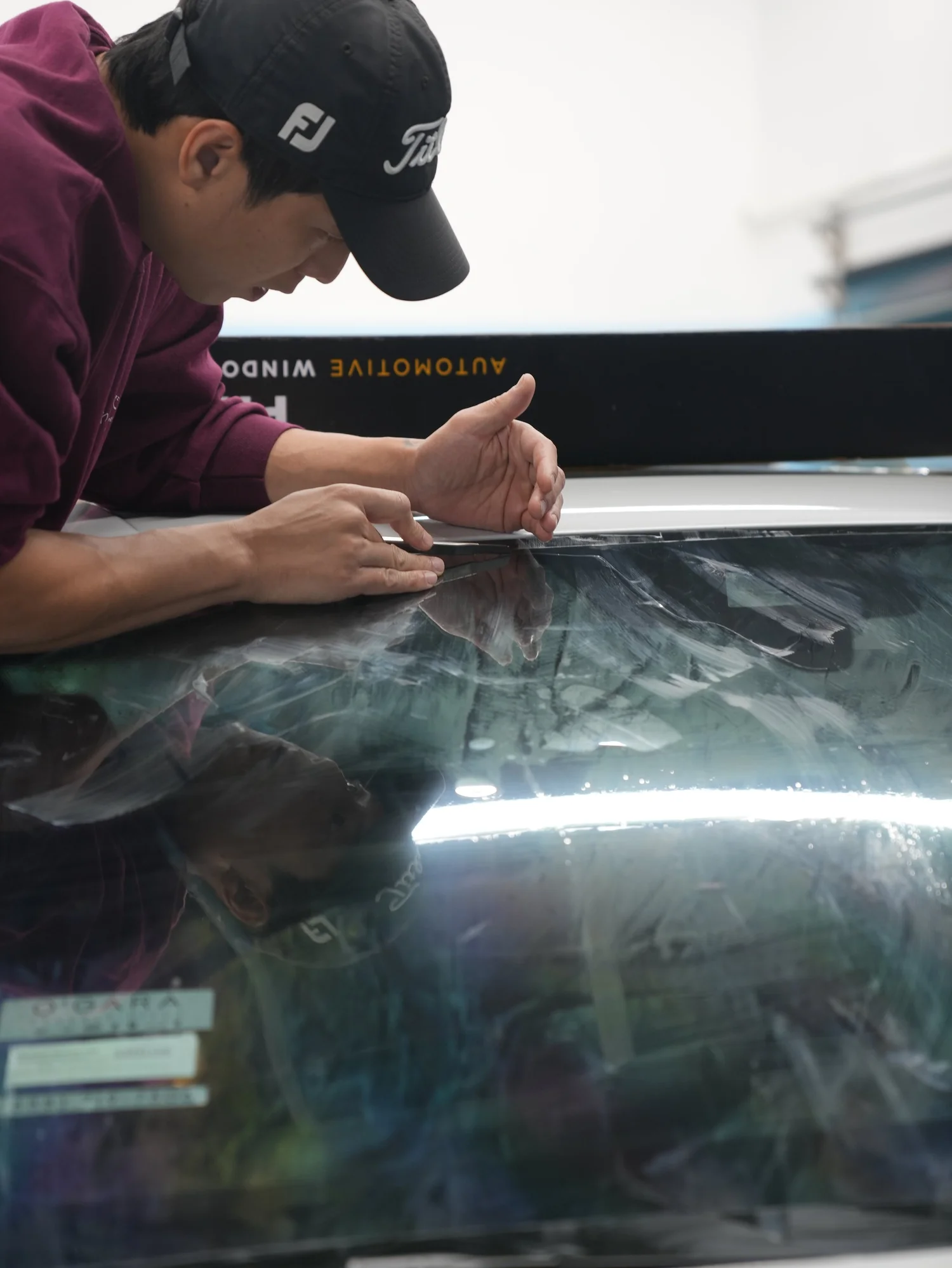 Lamborghini Urus Performante installer applying film along the upper windshield and roof edge after full exterior PPF, window tint and ceramic coating