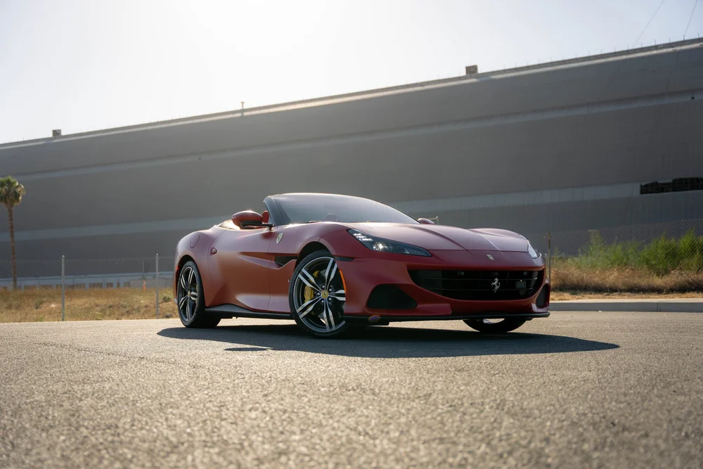 Red Ferrari Portofino in a complete low front three-quarter view with lowered roof, two-tone wheels and yellow brake calipers