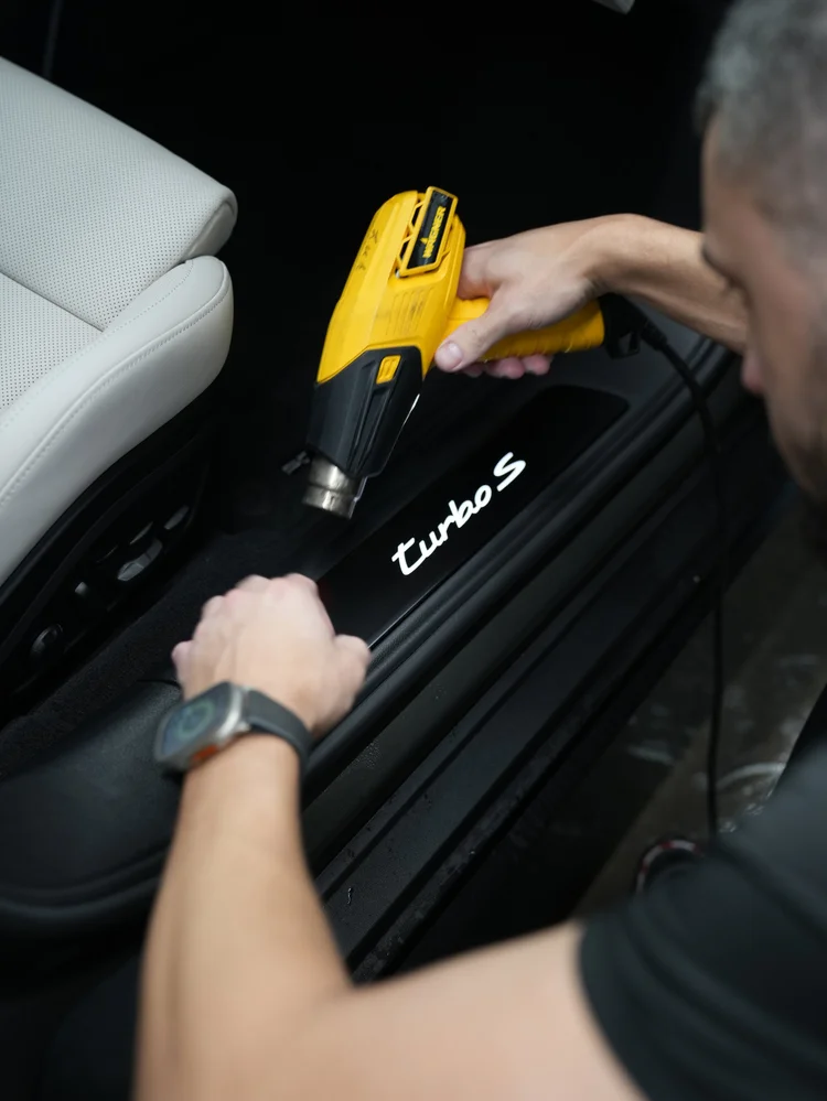 Yellow hot-air tool held above the illuminated Turbo S door sill and cabin floor area