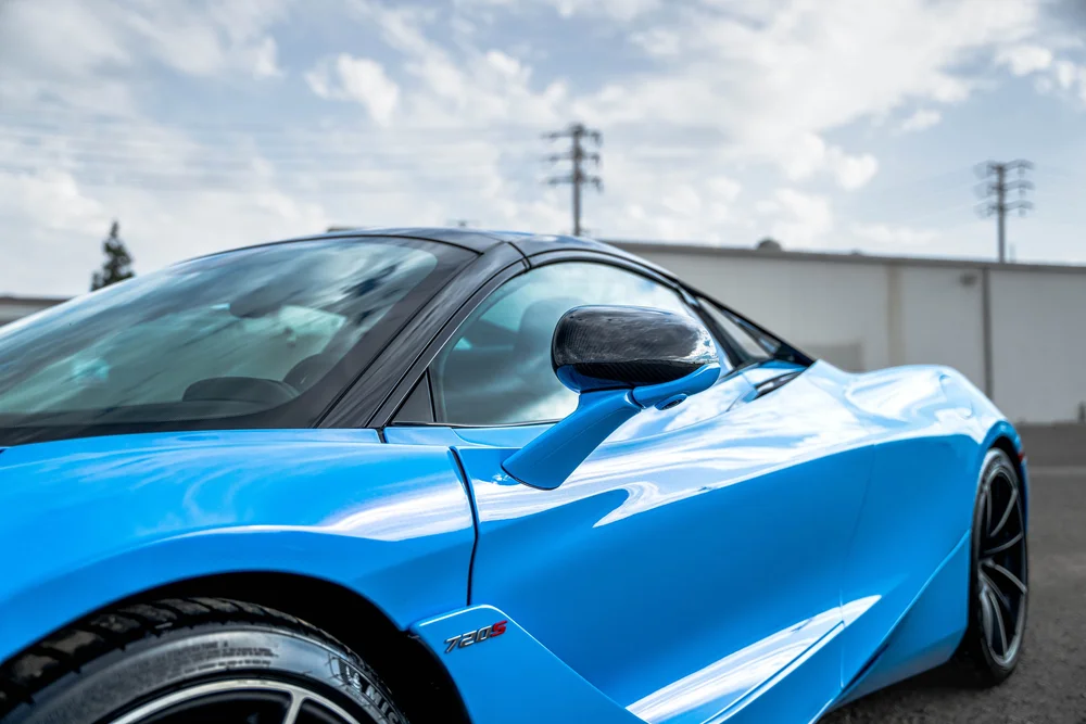 Blue McLaren 720S side bodywork with its door closed, side glass, dark mirror and sculpted side channel