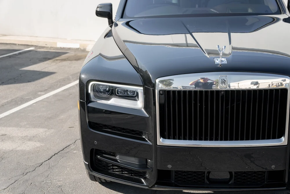 Dark Metallic Grey Rolls-Royce Cullinan — elevated front detail of the hood, ornament, grille and headlamp area
