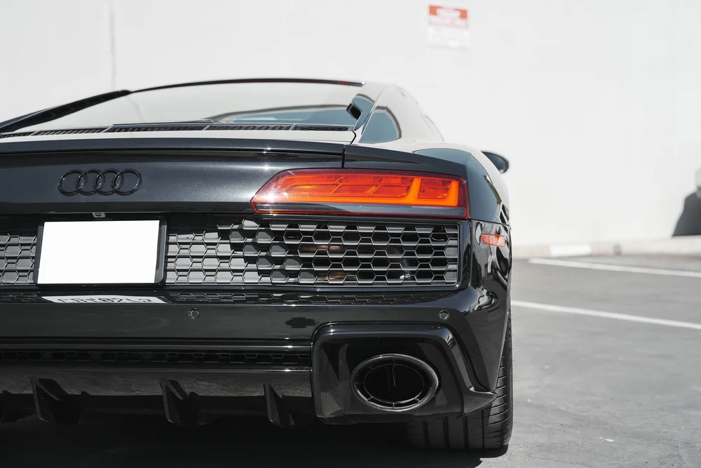 Closer rear view of the black R8 with Audi rings, taillight, dark grille and large exhaust outlet