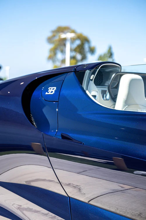 Bugatti W16 Mistral Blue Carbon side panel and EB badge beside the intake, with a light-colored seat beyond