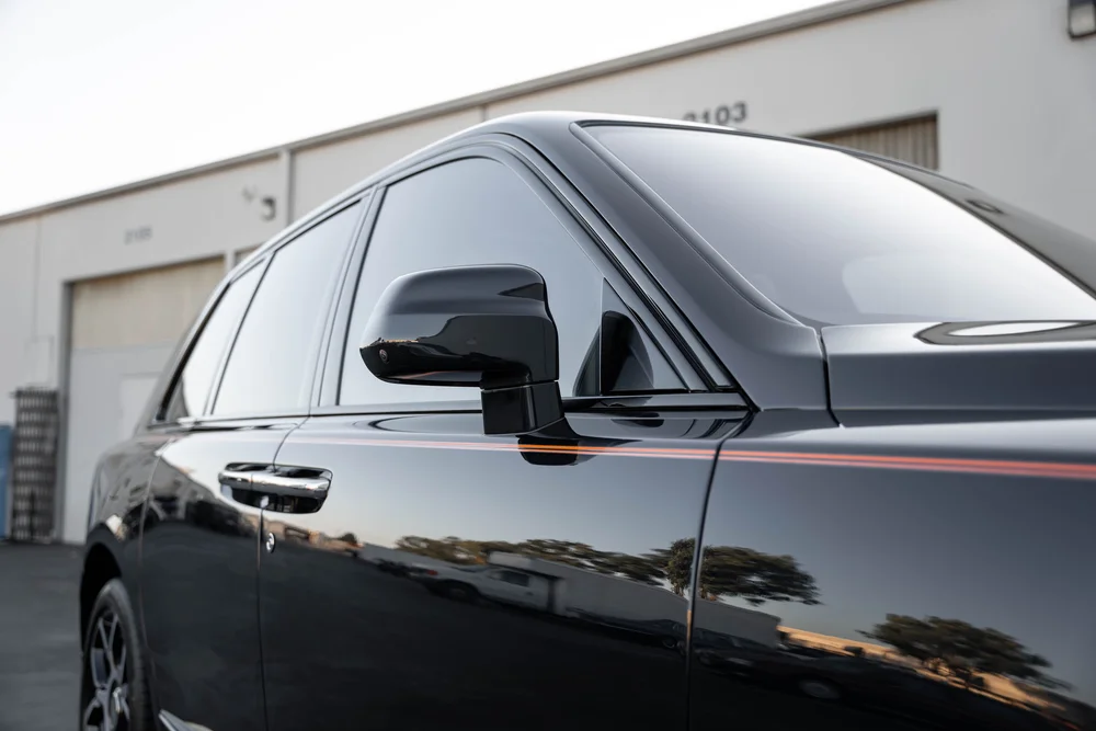 Black Rolls-Royce Cullinan Black Badge — side glass, mirror and adjacent dark bodywork in a landscape detail