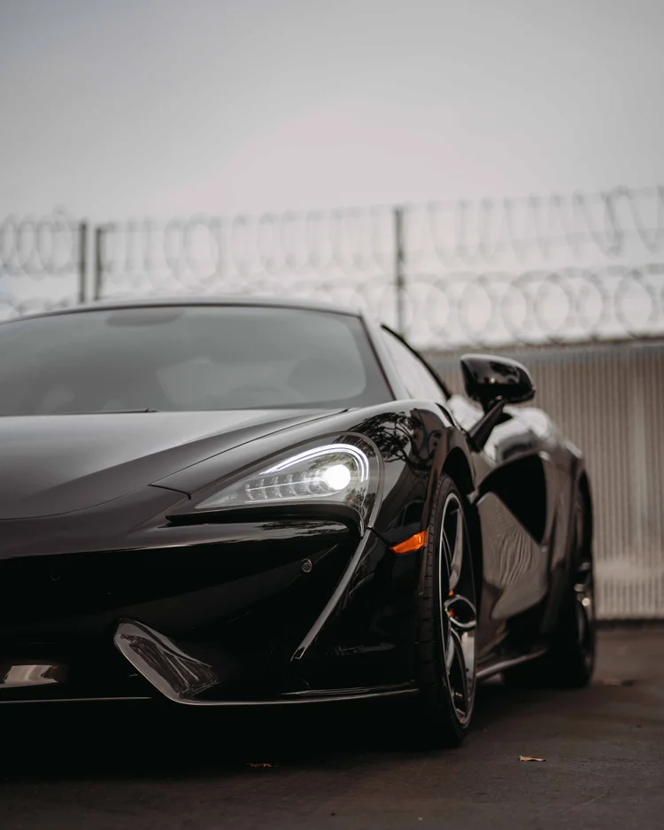 Cropped front-quarter portrait showing the bright headlamp, orange caliper and sculpted side opening.