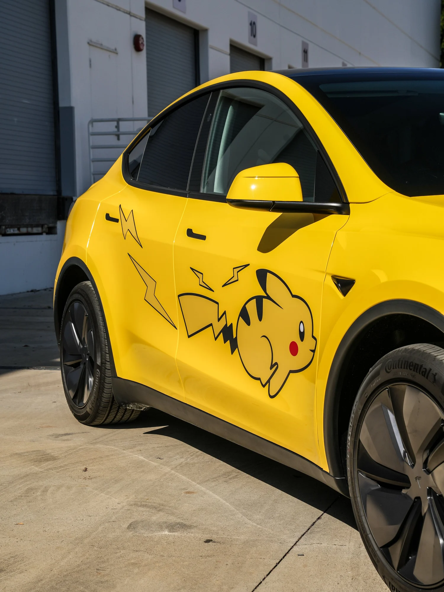 Tesla Model Y Vegas Yellow wrap with Pikachu door graphic, driver-side detail