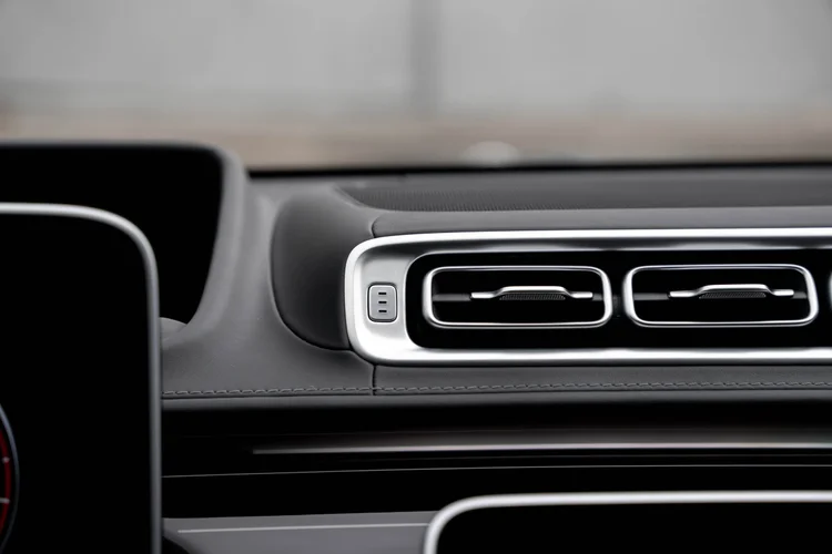 Paired horizontal dashboard vents with bright surrounds above dark stitching and striped trim
