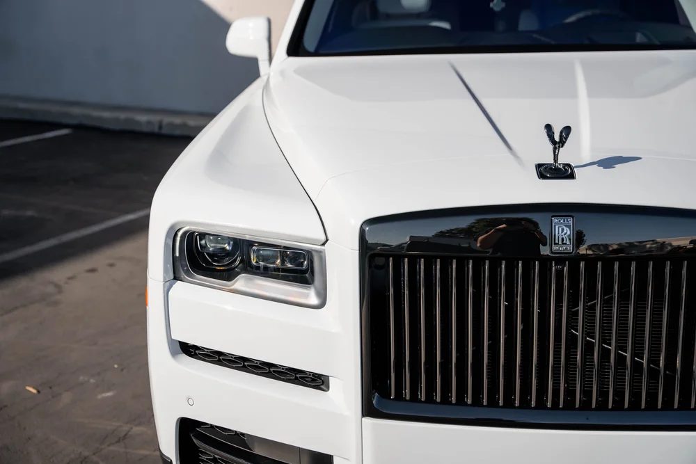 White Rolls-Royce Cullinan — hood ornament, white hood, grille and headlamp in an elevated close view