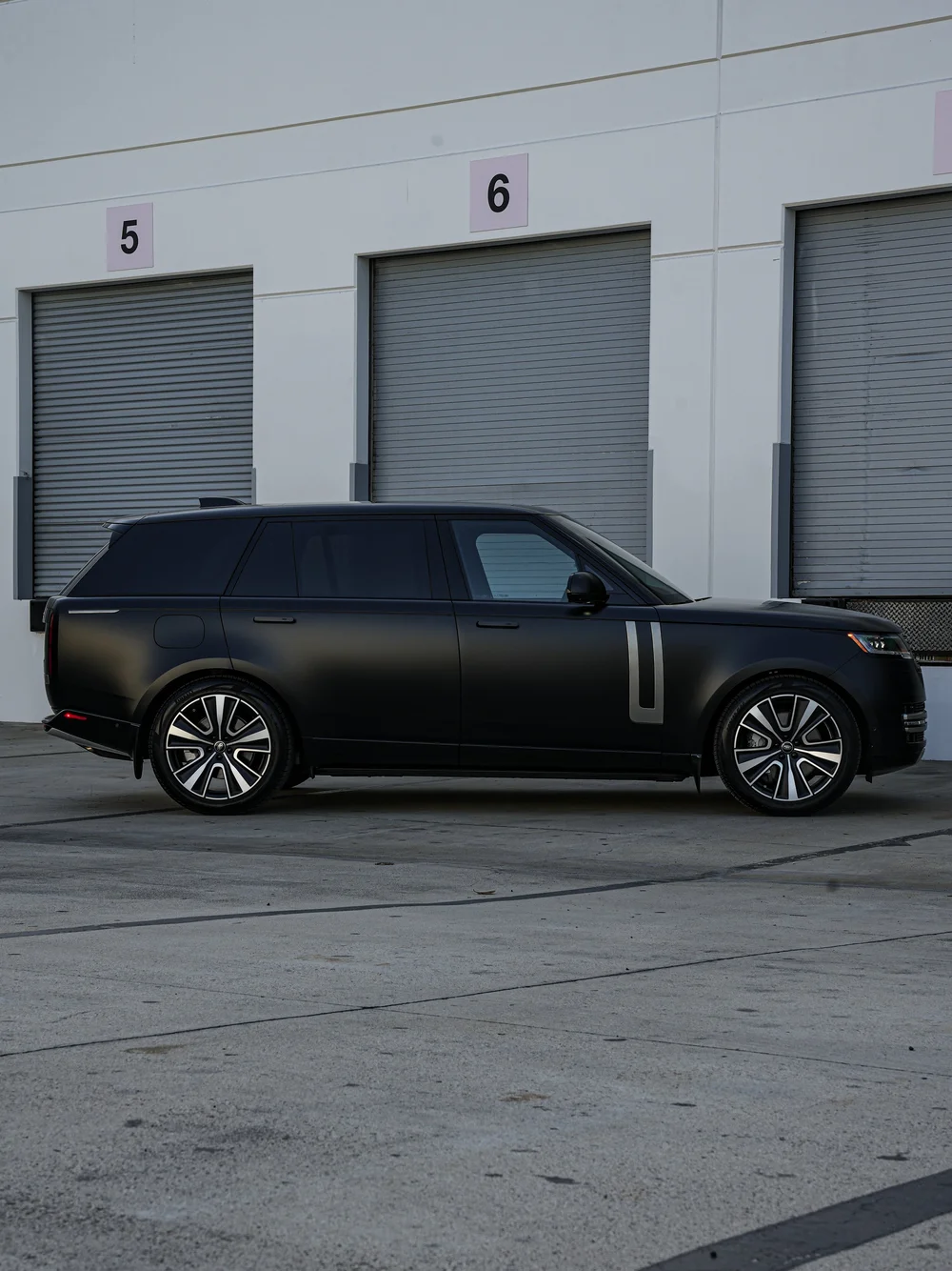 Full side profile of the black Range Rover with dark glass, silver side trim and two visible wheels.