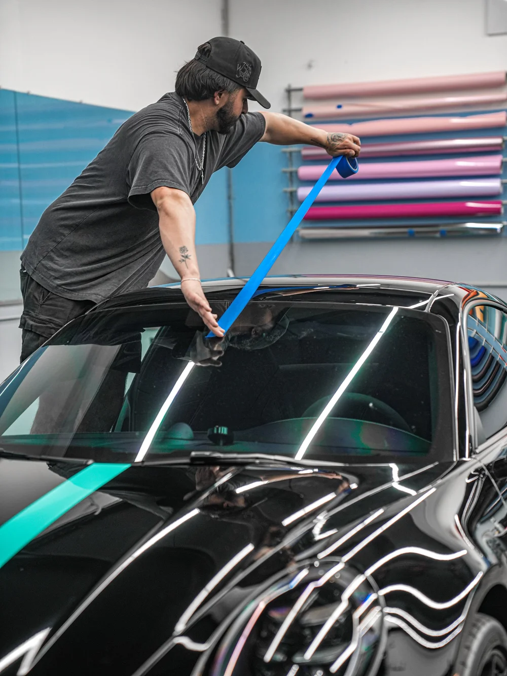 Technician using blue alignment tape above the windshield of the Porsche 911 Carrera 4 GTS during the graphics work
