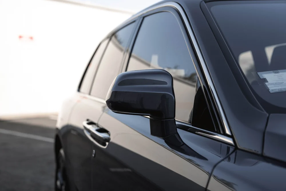 Dark Blue Rolls-Royce Cullinan — side glass and mirror above reflected body-panel details in a landscape view