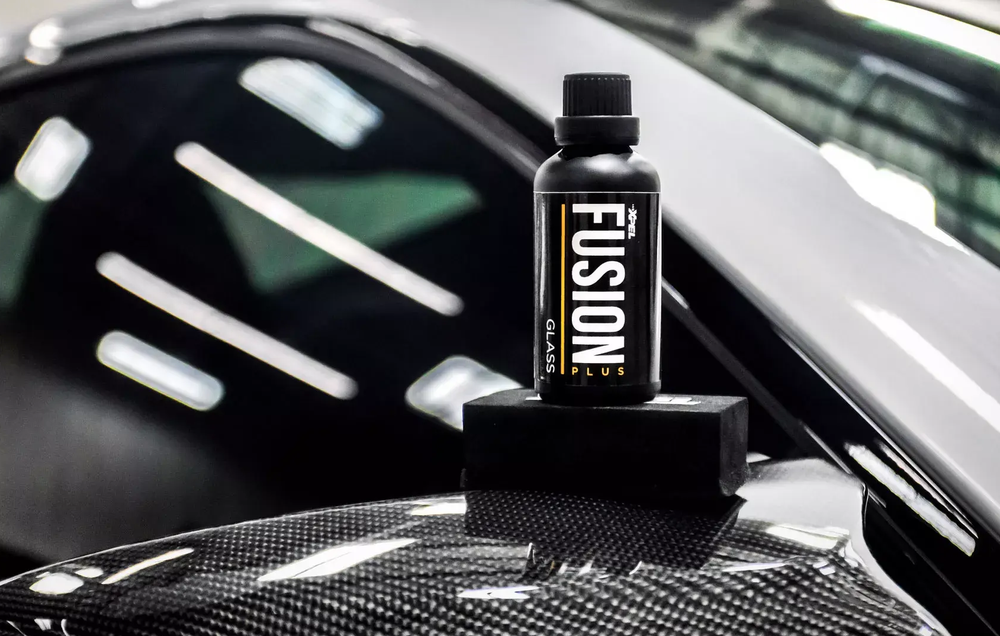 XPEL FUSION PLUS glass coating displayed on a carbon-fiber vehicle surface.