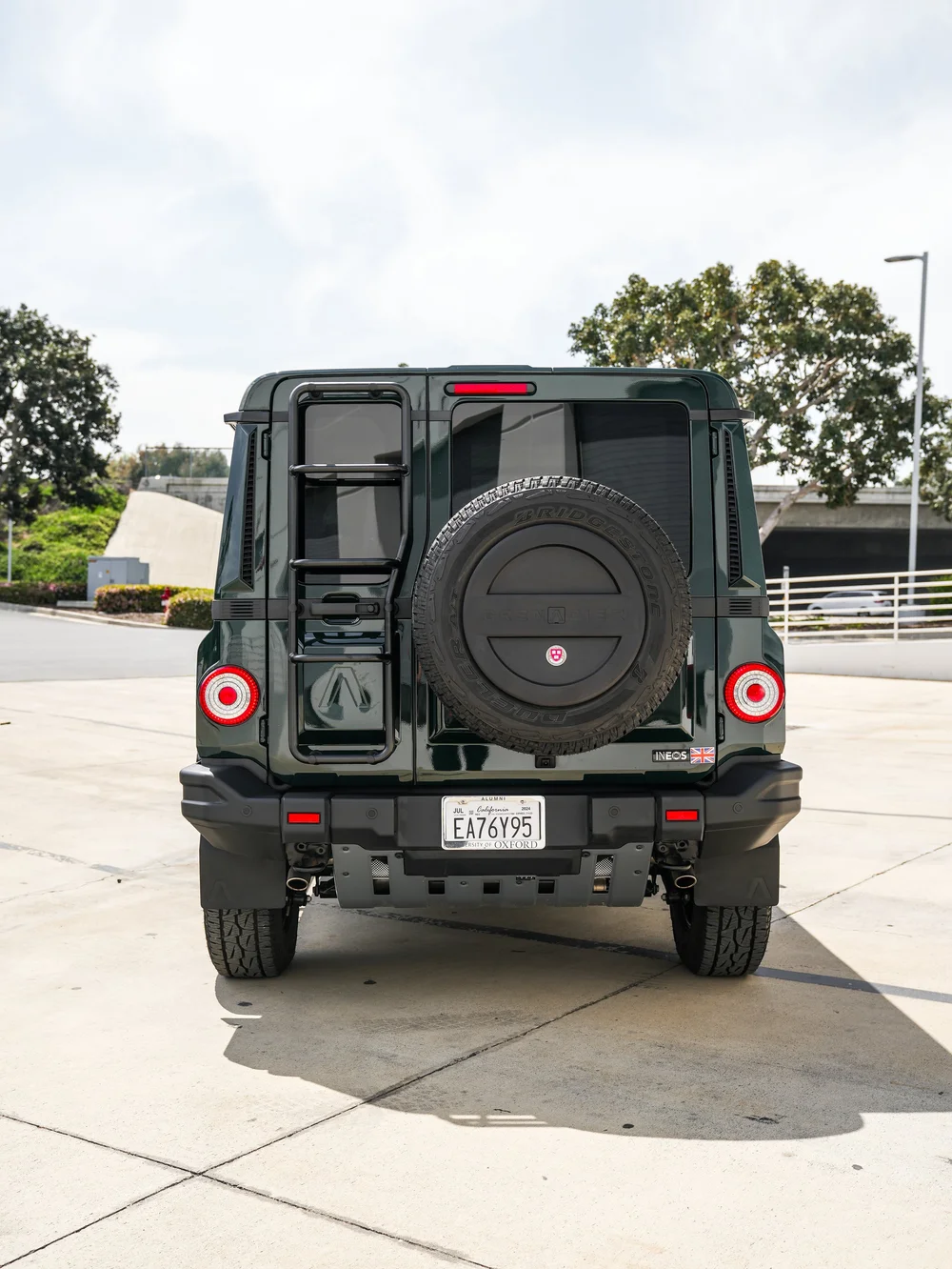 Straight rear view of the green INEOS Grenadier with rear-mounted spare wheel, ladder and circular tail lamps.