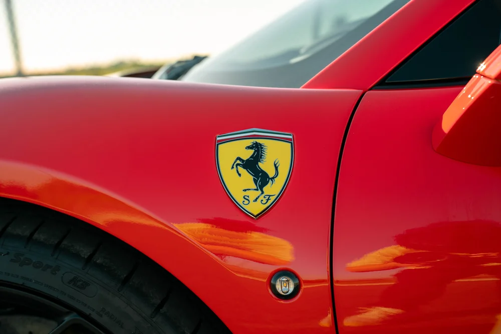 Ferrari shield on the red F8 front fender beside a reflective paint surface and door seam