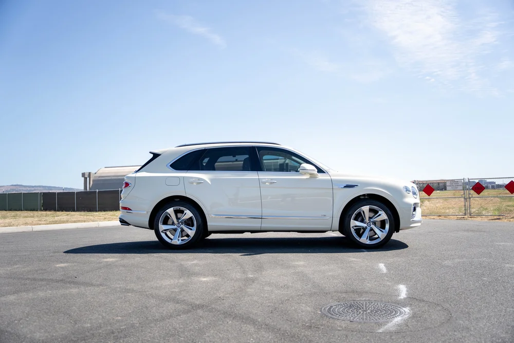Full side profile of the white SUV with silver wheels against blue sky.