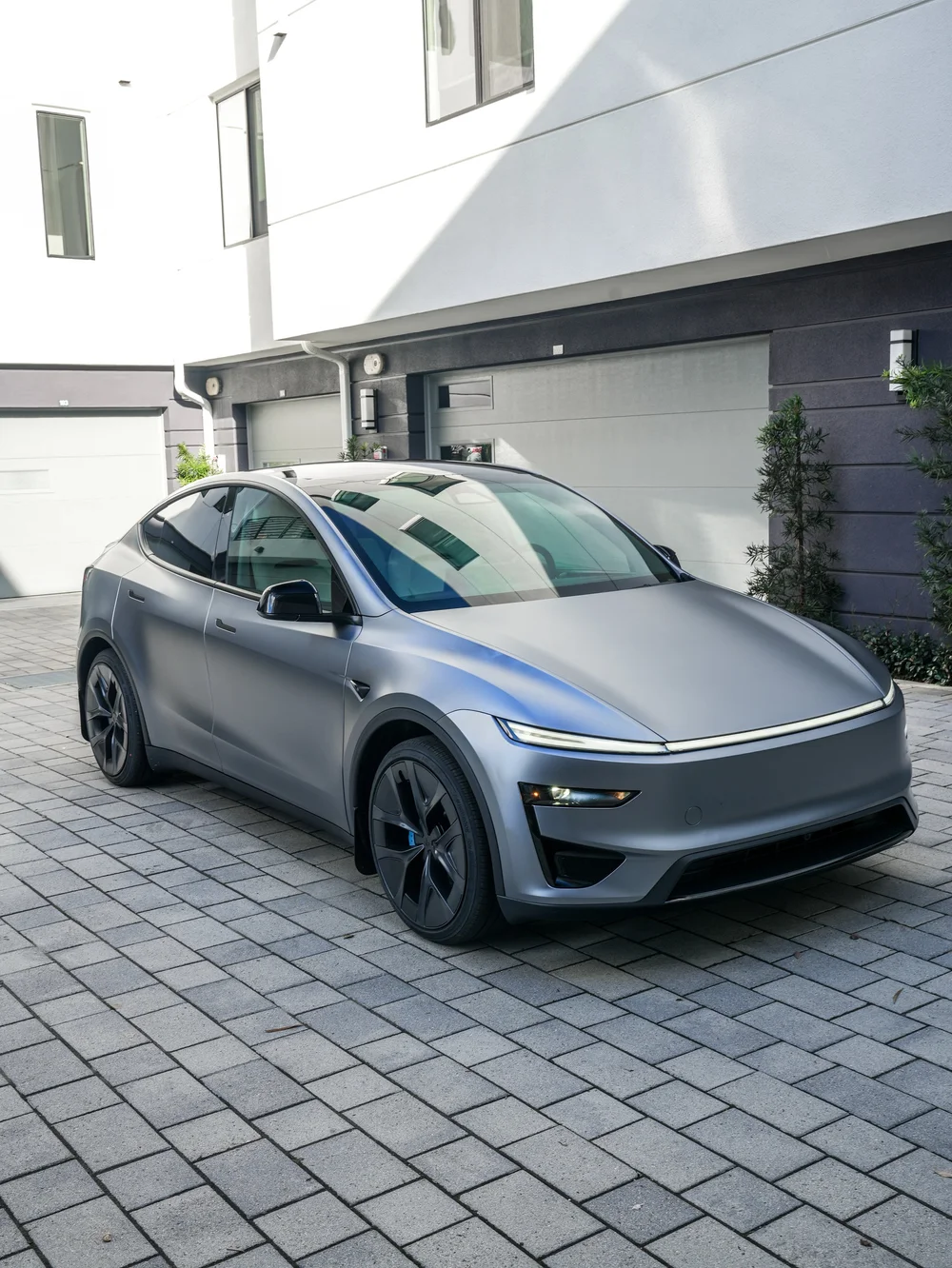 Front three-quarter view of the satin Quicksilver Model Y Performance, with the gloss-black mirror and lower front insert visible.