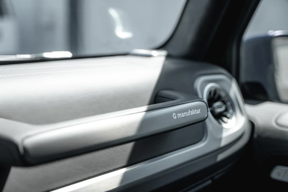 Passenger-side grab handle marked G manufaktur beside a circular vent and grey G 550 dashboard trim