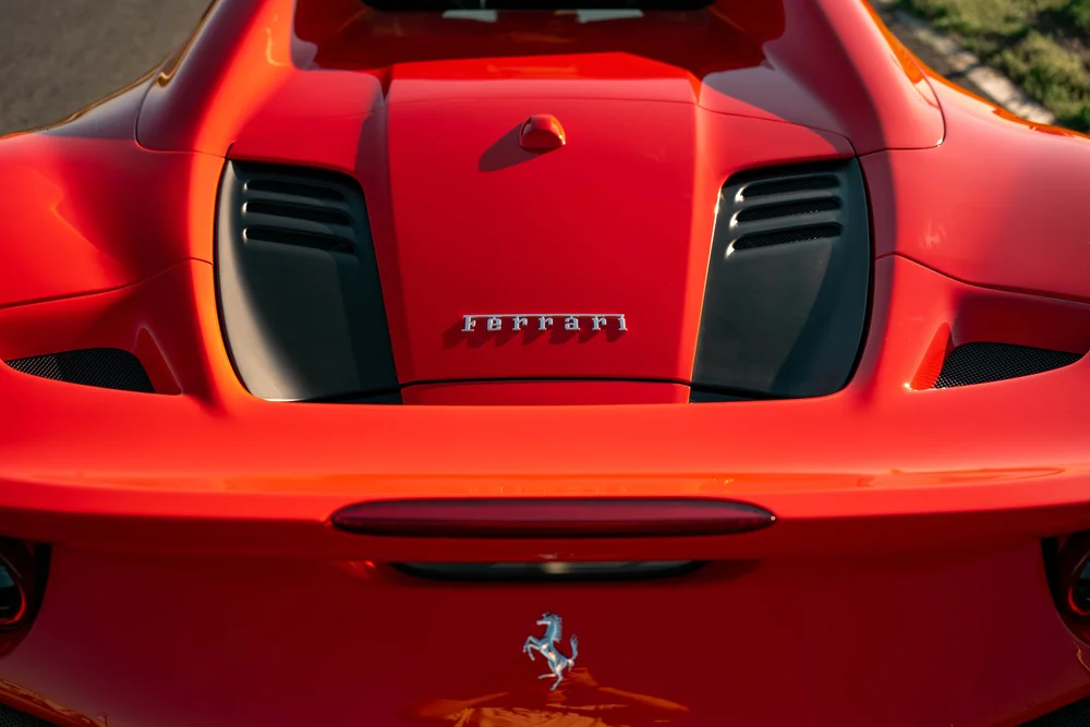 High rear-deck detail of the red Ferrari F8 showing glossy red paint and dark vent panels