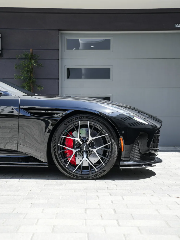 DB12 front wheel and red brake caliper beside its fender vent and front corner.