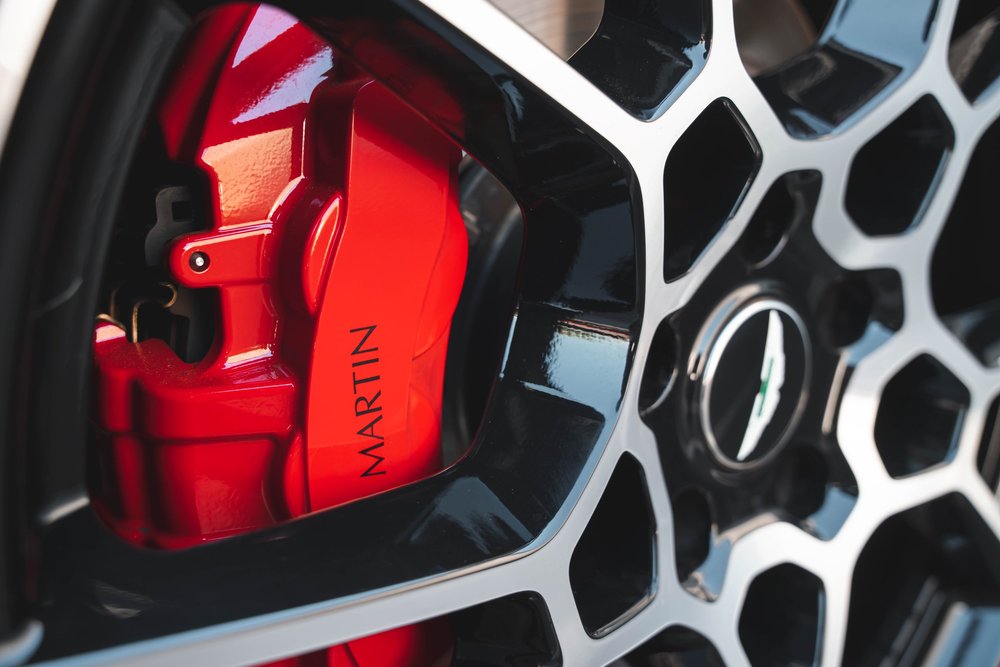 Red Aston Martin brake caliper behind the black-and-silver wheel spokes.