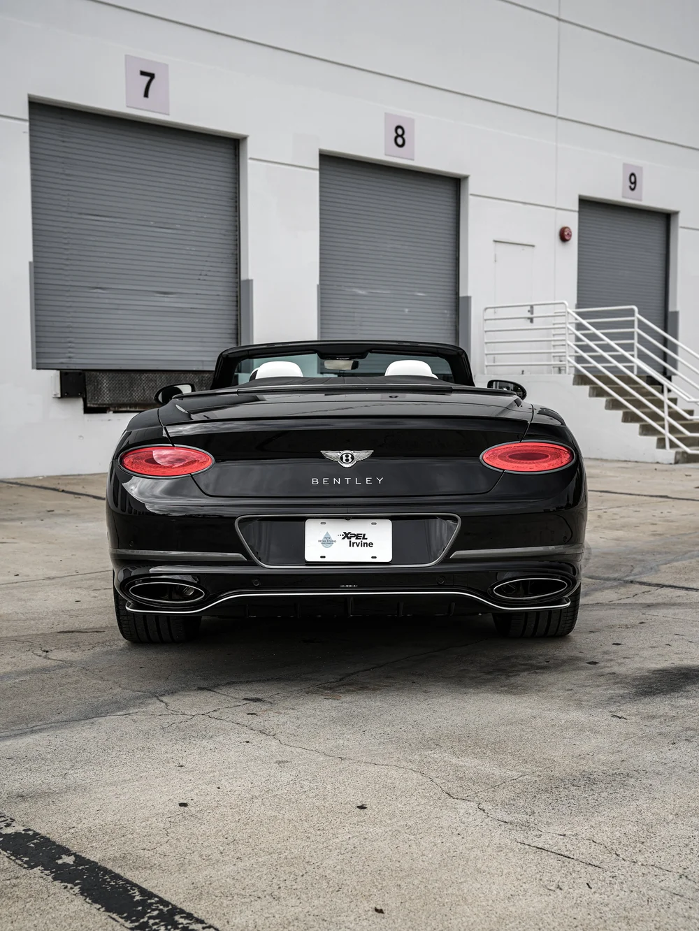 Straight rear view of the Onyx Black Bentley Continental GTC with oval taillamps, twin exhaust outlets and the XPEL Irvine display plate.