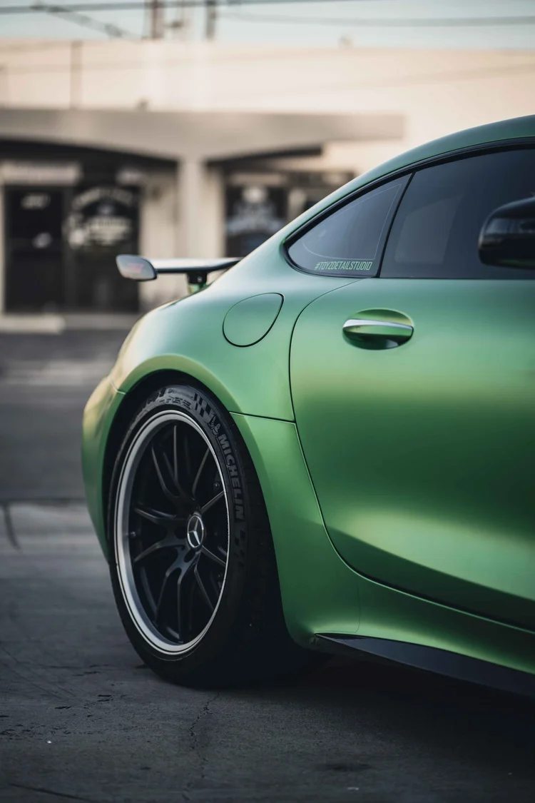Partial green rear quarter with a dark rear wheel, door handle, fuel door and black wing tip.