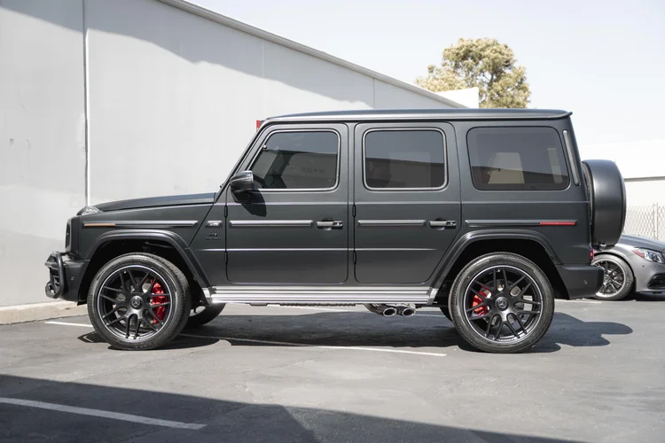 Complete side profile of the grey G 63 with dark wheels, red calipers, silver running boards and twin side exhaust tips
