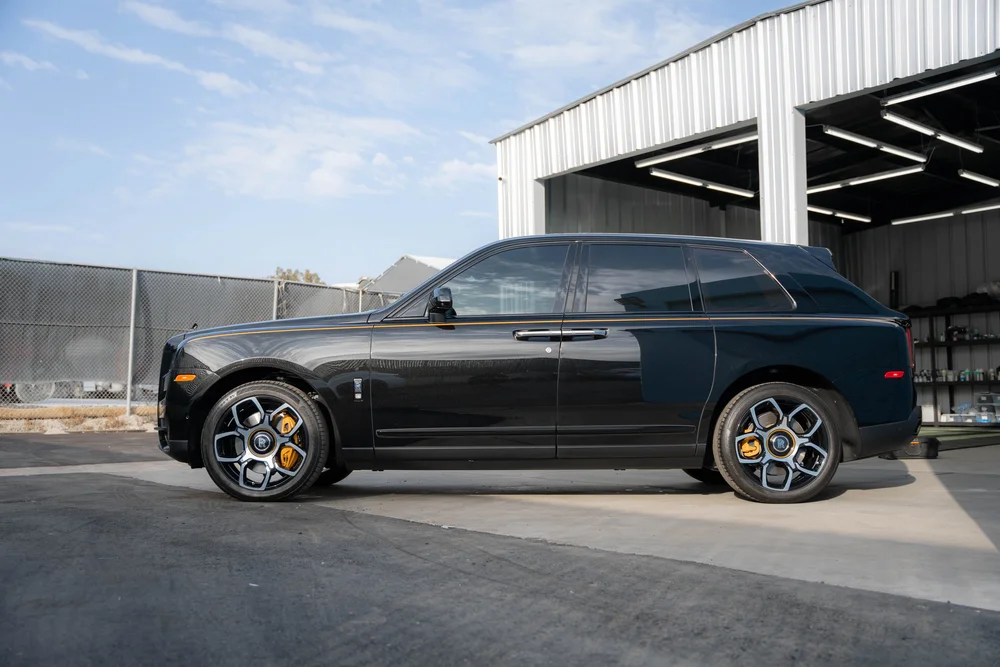 Side profile of the black SUV with yellow calipers behind the wheels.