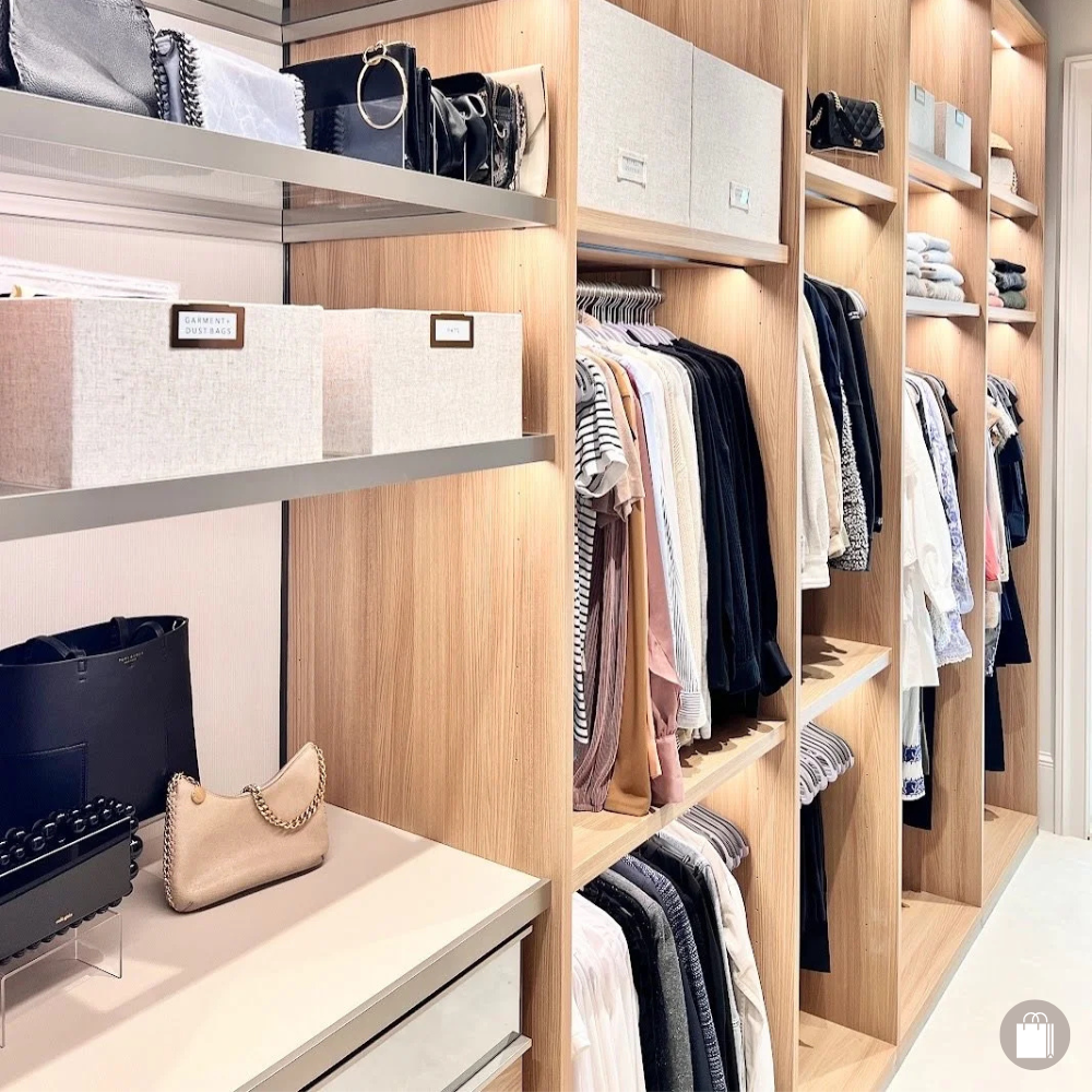 Upscale custom closet with linen-labeled bins, beautifully displayed handbags, and illuminated clothing rods, meticulously organized by Sorted Professional Organizing in New Orleans.