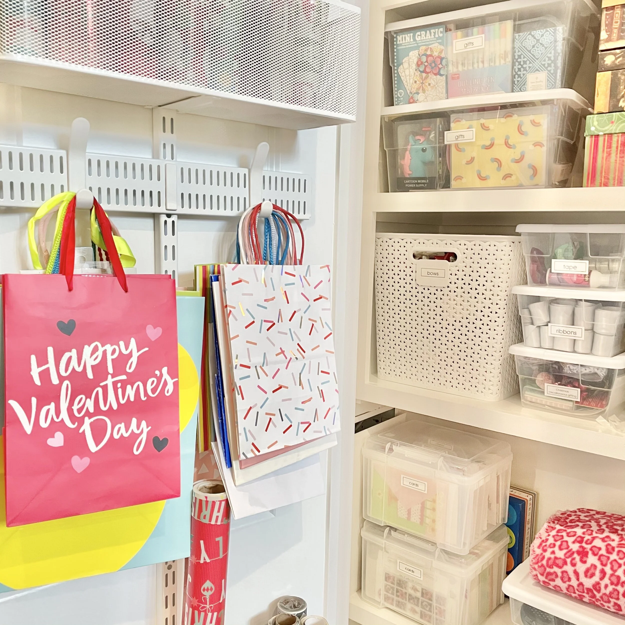 Elfa over-the-door utility track with white mesh metal baskets and hooks for holiday gift wrapping station organized by Sorted Professional Organizers in New Orleans.