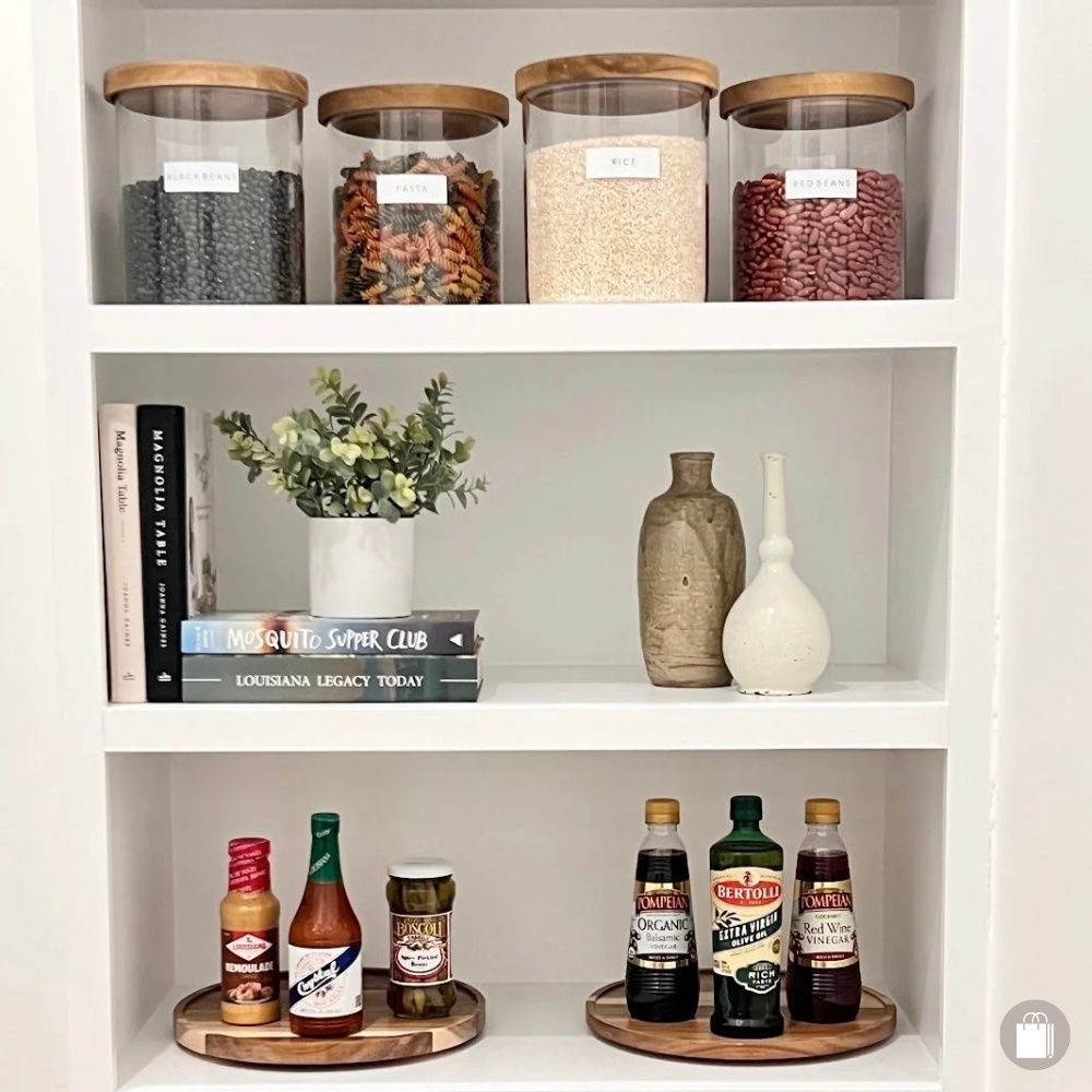 Kitchen shelving with spices on turntables, glass canisters with wooden lids, and neatly arranged cookbooks, all organized by Sorted Professional Organizing.