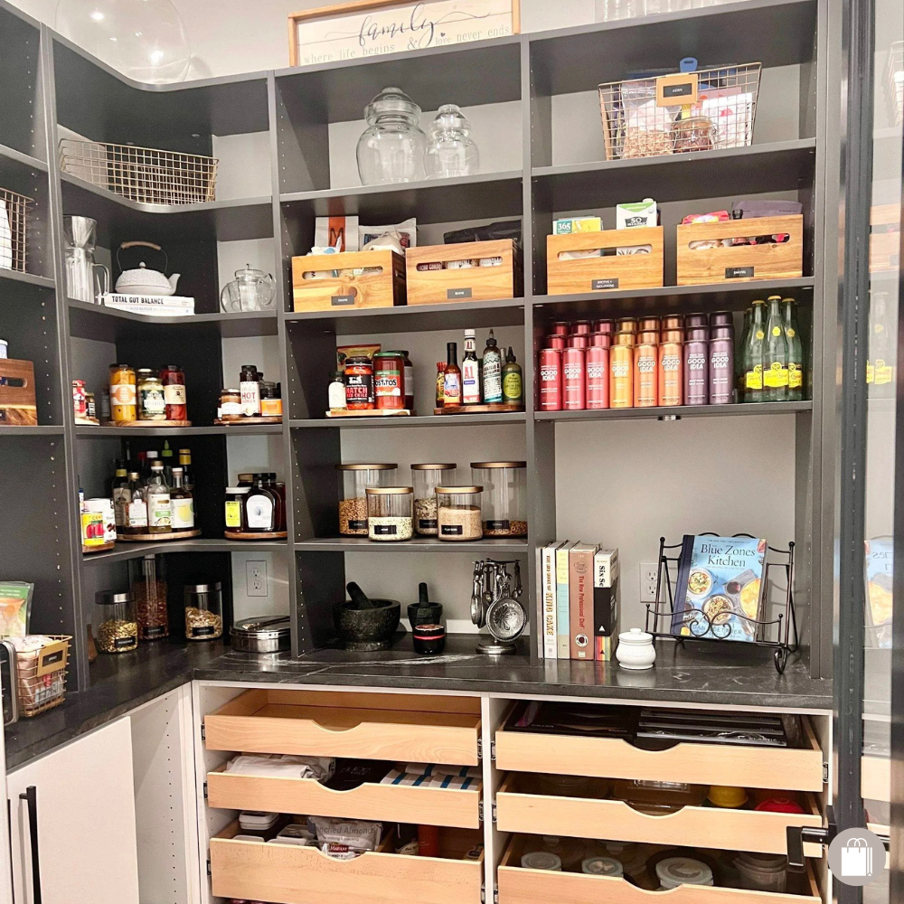 Pantry shelves with various jars, bottles, and boxes of food and spices, with wooden drawers containing pantry items at the bottom, and decorative frames and jars on the top.