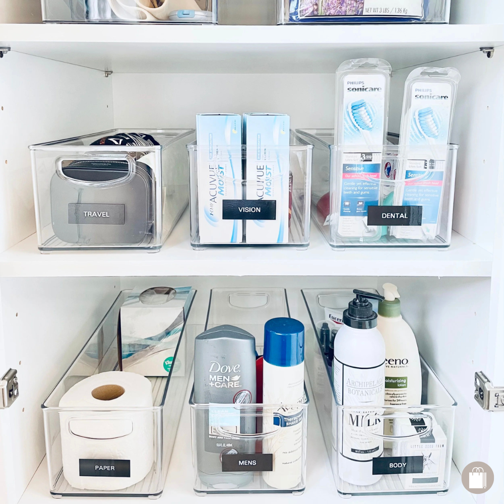 Bathroom cabinet efficiently organized with The Home Edit acrylic bins and labeled for easy access, organized by Sorted Professional Organizing in New Orleans.