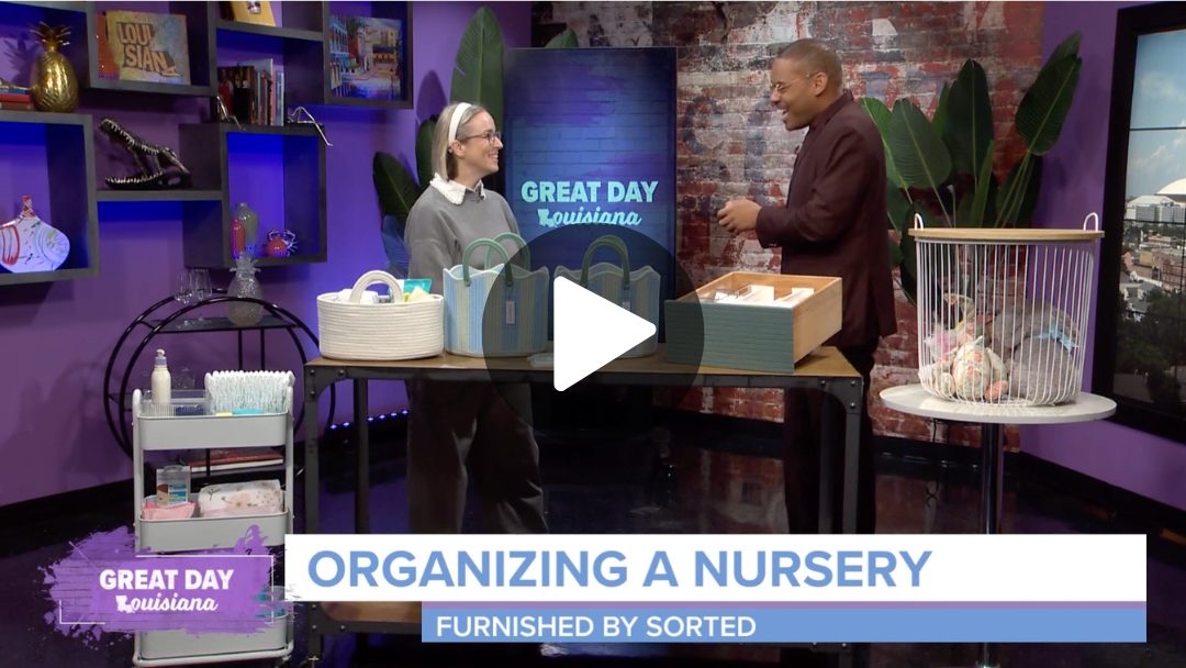 Sorted founder Victoria Tran with morning host Malik Mingo on WWL set smiling and talking about organizing a nursery, with shelves of toys and books, and a large screen displaying 'Great Day Louisiana' in the background.